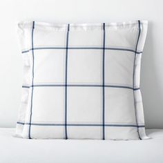 a white and blue plaid pillow sitting on top of a bed