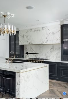 a large kitchen with marble counter tops and black cabinetry, along with a chandelier