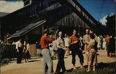 an old photo of people standing in front of a barn