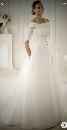 a woman in a white wedding dress posing for the camera with her hands on her hips