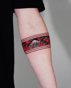 a woman's arm with a tattoo on it that has mountains and red flowers