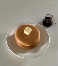 a plate with a piece of cheese on it next to a cup of coffee and saucer