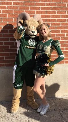 two people dressed up as cheerleaders standing in front of a brick wall with their arms around each other