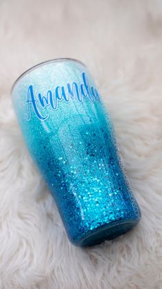 a blue glass with the word amanda on it sitting on a white furnishing