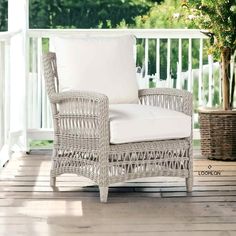 a white wicker chair sitting on top of a wooden deck next to a potted plant