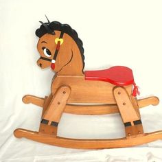 a wooden rocking horse with a red seat on it's back and black hair