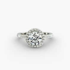 a white gold engagement ring with an oval halo setting and pave set diamonds around the band