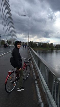 a man standing next to a bike on a bridge