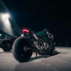 a black motorcycle parked in front of a building at night with its lights turned on