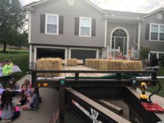 children sitting on the ground in front of a house with hay bales attached to it