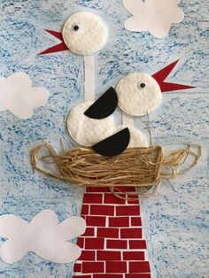 a paper bird sitting on top of a red brick wall with white clouds above it