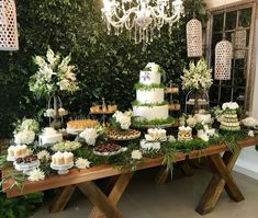 a table topped with lots of food and greenery next to a chandelier