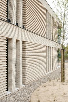 the side of a brick building with several vertical bricks on it's sides, along with gravel and grass