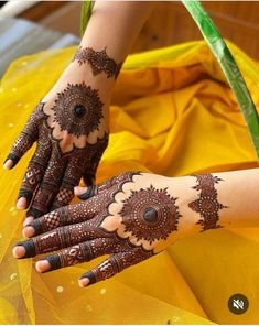 a woman's hands with hennap on it and yellow cloth in the background