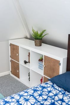 a bed with a plant on top of it next to a white book shelf in a bedroom