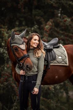 a beautiful woman standing next to a brown horse