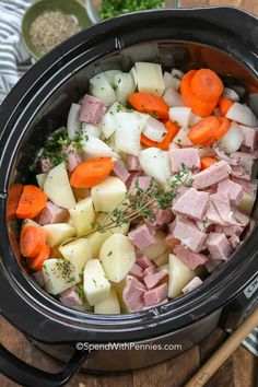 ham, potatoes and carrots are in the crock pot on the wooden table