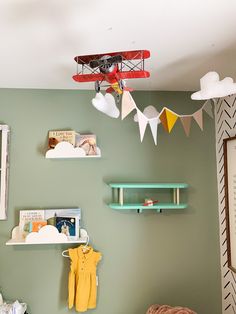 a baby's room with green walls and shelves