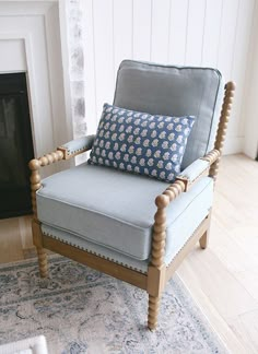 a blue chair sitting on top of a wooden floor next to a fire place in a living room