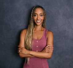 a woman with her arms crossed posing for a photo in front of a gray background