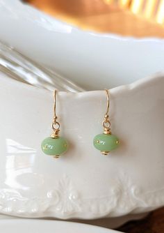 Using the same glass as the jade chrysalis, I've created a set of matching earrings. A refined, elegant companion to your Monarch chrysalis replica necklace in the same jade colored glass. Four 24k gold dots are perfectly placed on the bead. The findings are 14k gold-filled. I'm so happy to finally be offering these. Many people opt for the complex miniature chrysalis earrings, but it's lovely to be able to offer a simple, inexpensive option as well. Please note, if purchased with another piece, Elegant Hypoallergenic Glass Earrings, Gold Hypoallergenic Jade Earrings, Hypoallergenic Gold Jade Earrings, Jade Wire Wrapped Earrings For Gifts, Wire Wrapped Jade Earrings As Gift, Elegant Green Czech Glass Earrings, Elegant Wire Wrapped Earrings For May Birthstone, Elegant Light Green Earrings As Gift, Elegant Light Green Earrings For Gift