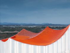 an orange and white structure with mountains in the background