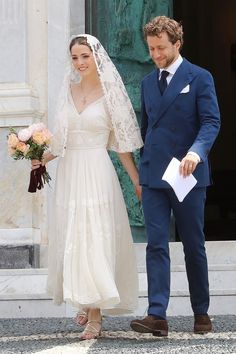 the bride and groom are holding hands as they walk out of the church door together