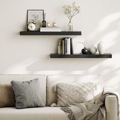 a living room with white walls and two black shelves on the wall above the couch