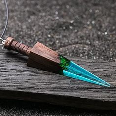 a pair of blue and green earrings sitting on top of a piece of wood