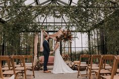 a bride and groom standing in front of an outdoor wedding ceremony area with wooden chairs