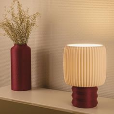 two vases sitting on top of a shelf next to each other with flowers in them