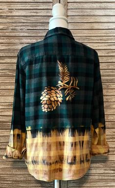 a green and yellow flannel shirt with pineapples on the chest, sitting on a mannequin head