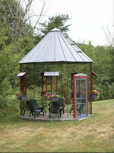 a gazebo in the middle of a grassy area with chairs and tables around it