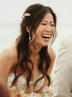 a woman in a wedding dress smiles as she sits next to a man wearing a suit and tie