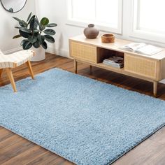 a blue rug in a living room with a chair and potted plant on the side