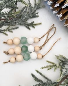 some white and green beads hanging from a pine tree