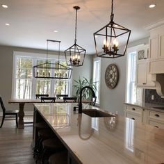 a large kitchen with an island in the middle and two hanging lights on the ceiling