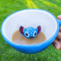 someone holding a blue and white bowl with a small toy in it's mouth