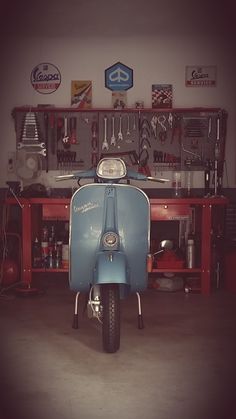 a blue scooter parked in front of a workbench filled with tools