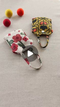 two small purses sitting next to each other on a table with pom poms