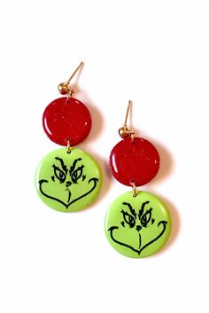 two red and green earrings with the grin face painted on them, hanging from gold earwires