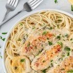 a white plate topped with pasta covered in sauce and parmesan sprinkles