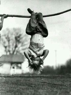 two young boys are playing with a stick in the air while one boy is upside down