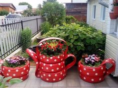 some red and white polka dot pots with flowers in them on the side of a house