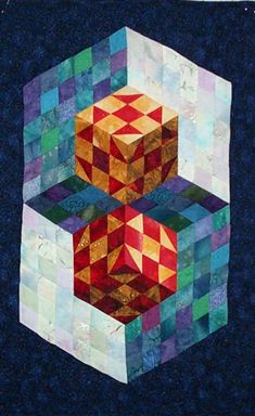 a quilted wall hanging with two cubes on it's sides and one block in the middle