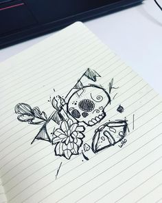 a notepad with a drawing of a skull and flowers on it next to a laptop