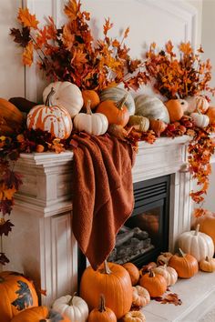 a fireplace decorated with pumpkins, leaves and other autumn decorations on top of it