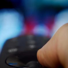 a close up of a person's hand holding a remote control with blurry background