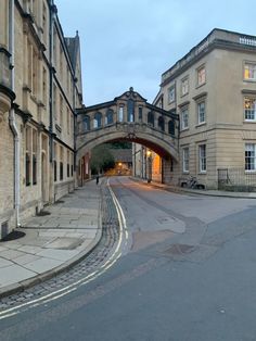 an arch in the middle of a street with buildings on both sides and a car driving under it