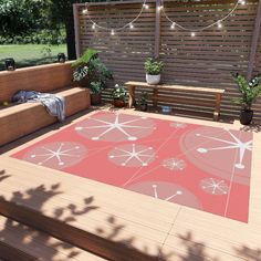 an outdoor area with wooden benches and plants on the deck, surrounded by string lights